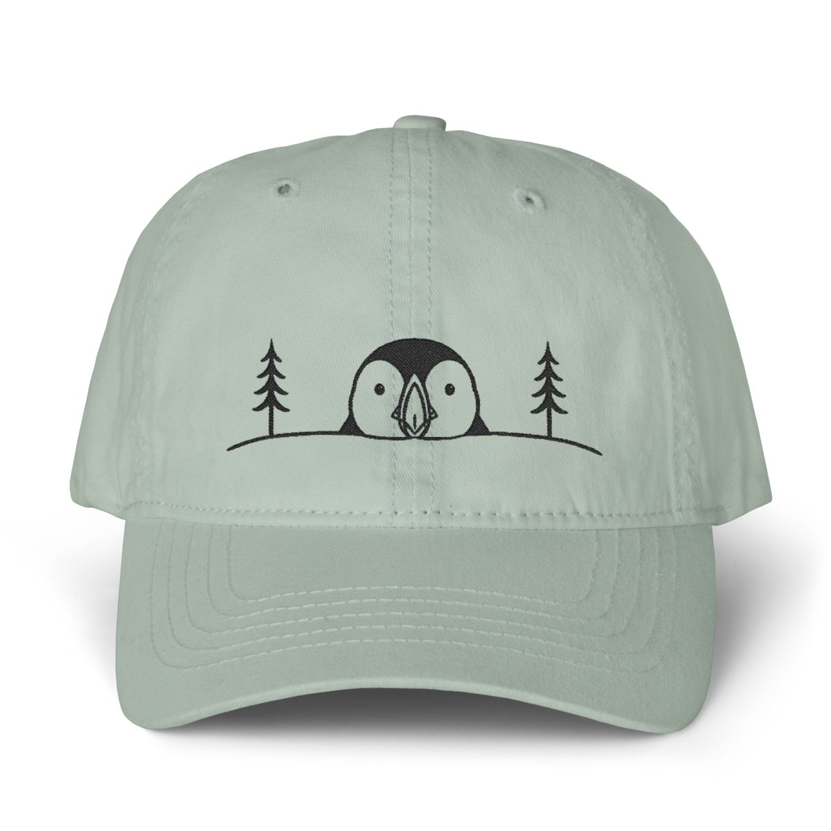 Sage green cotton dad hat with a minimalist black embroidered puffin between pine trees